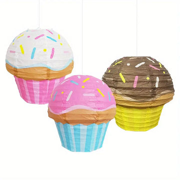 Set of three cupcake-shaped paper lanterns in white, pink, and brown with colorful sprinkles for party decor