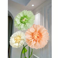 Elegant giant artificial flowers used as party wall backdrop for cake table setup.
